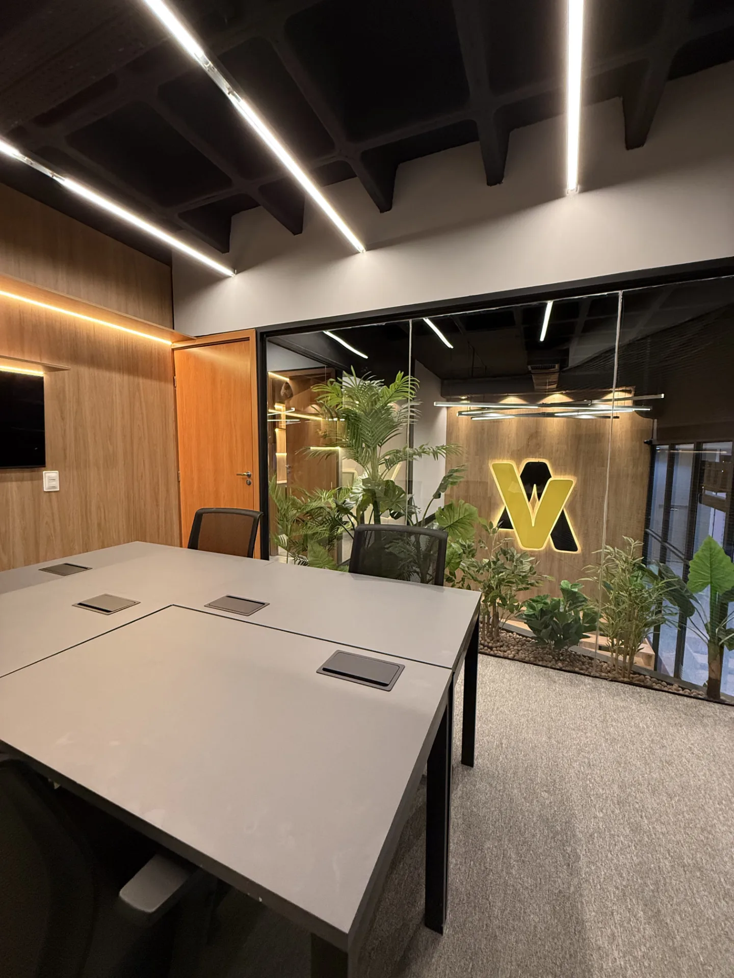 Sala de reunião com jardim interno e logo Virtua iluminado