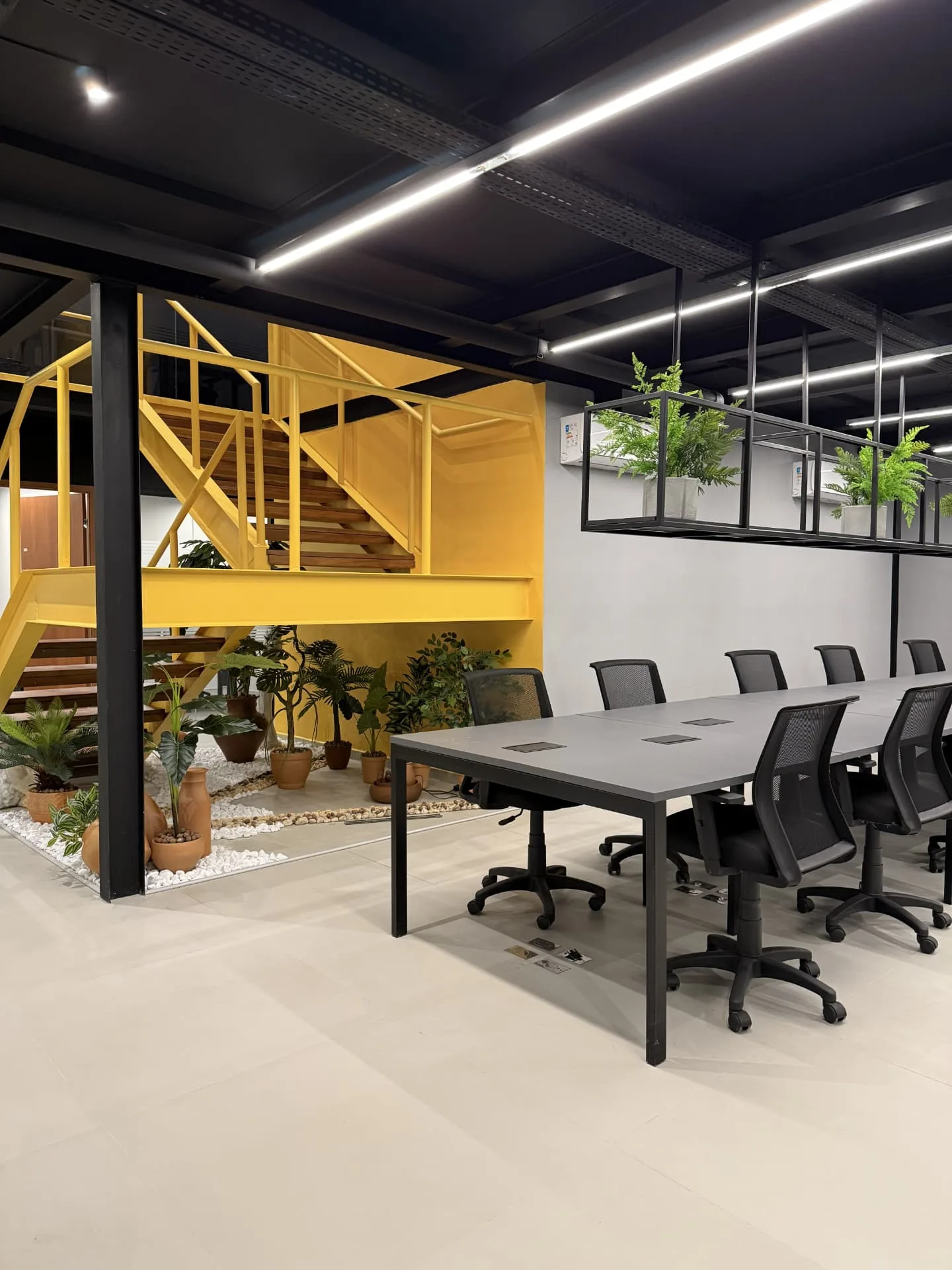 Área de coworking com mesa compartilhada e jardim interno